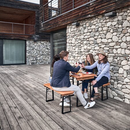 Four friends sit on the small beer garden table sets Shorty and toast together.