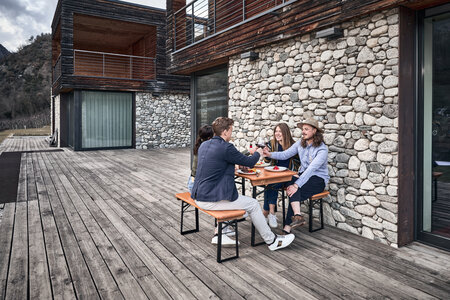 Four friends sit on the small beer garden table sets Shorty and toast together.