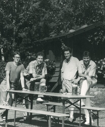 4 Personen stehen neben einer Bierzeltgarnitur. Ein Schwarz-Weiß-Foto das in Bezug steht zum Produktionsstart der Bierzeltgarnituren im Jahre 1986.
