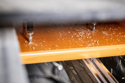 The photo shows a machine drilling holes into a beer bench.