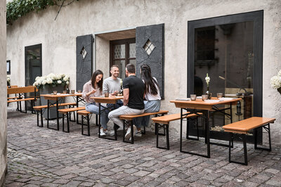 Four people are sitting on the small beer garden table set in the outdoor area of a restaurant.