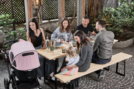 Six friends are sitting at a beer garden table set and eat peacefully.