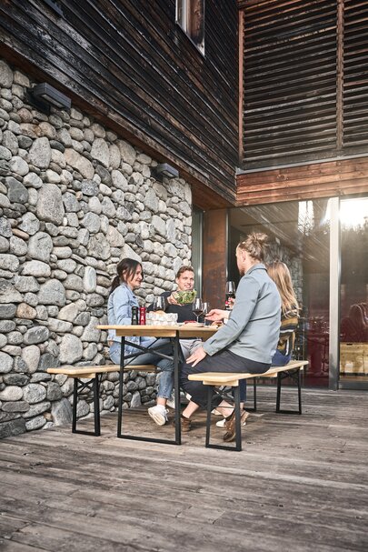 4 Personen genießen Ihre Mahlzeit auf einer Terasse auf der klassischen Bierzeltgarnitur in Natur.