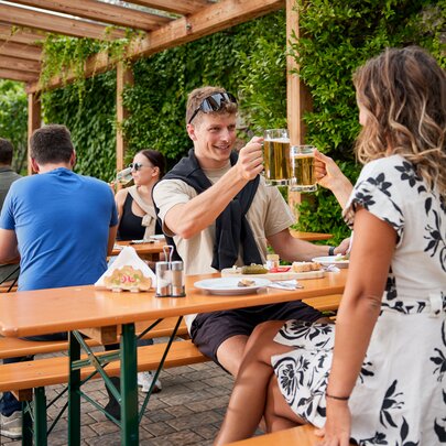 Mehrere Personen genießen auf den klassischen Bierzeltgarnituren die Marende und das Bier beim Guggerhof.