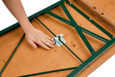 A hand pushes down the lever of the folding furniture lock to assemble the beer garden table set.