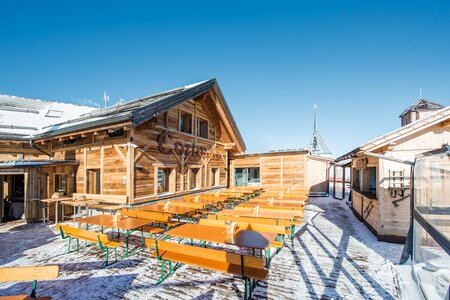 There are many wide beer garden table sets on a cottage in winter.