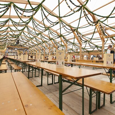The image shows the interior of an Oktoberfest tent with rows of RUKU1952 Classic beer tent sets.