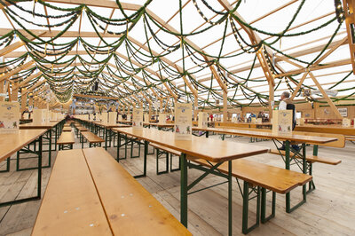 The image shows the interior of an Oktoberfest tent with rows of RUKU1952 Classic beer tent sets.