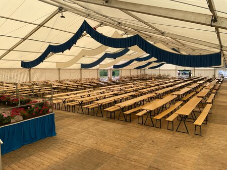 Beer garden table sets with legroom are placed in a marquee.